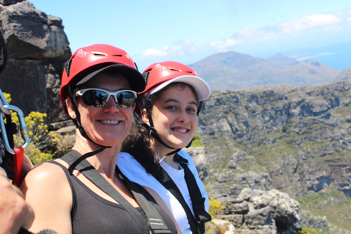 mom and daughter abseiling table mounting with the view of mountains in the background